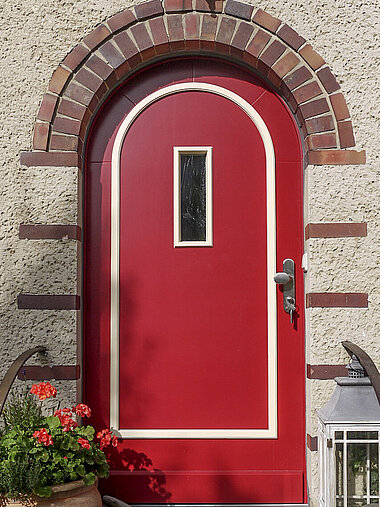 Nachgebaute Rundbogentür in rot mit weißen Akzenten