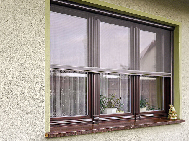 Fenster mit Insektenschutz-Rollo halb geöffnet