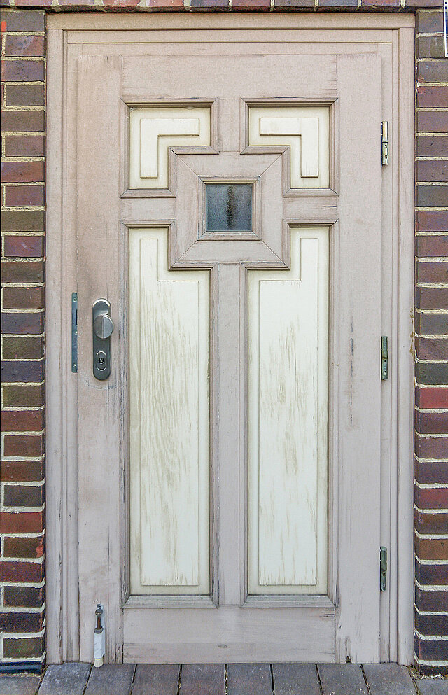 Alte Haustür mit speziellen, gewinkelten Füllungen, vom Wetter angegriffen