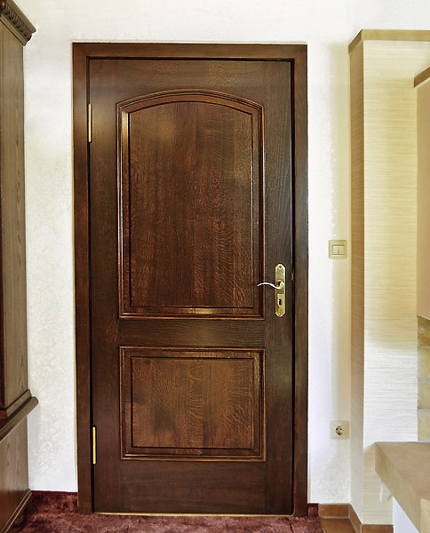 Die obere Füllung der Tür schließt elegant mit einem Segmentbogen ab.